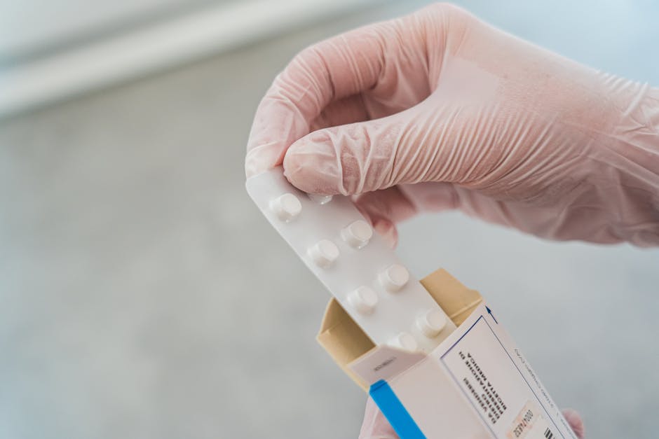 Close-up of a hand in gloves holding a blister pack of pills, symbolizing medical care.