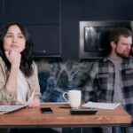 A couple in their kitchen, focused on financial planning and budgeting, showcasing stress and teamwork.