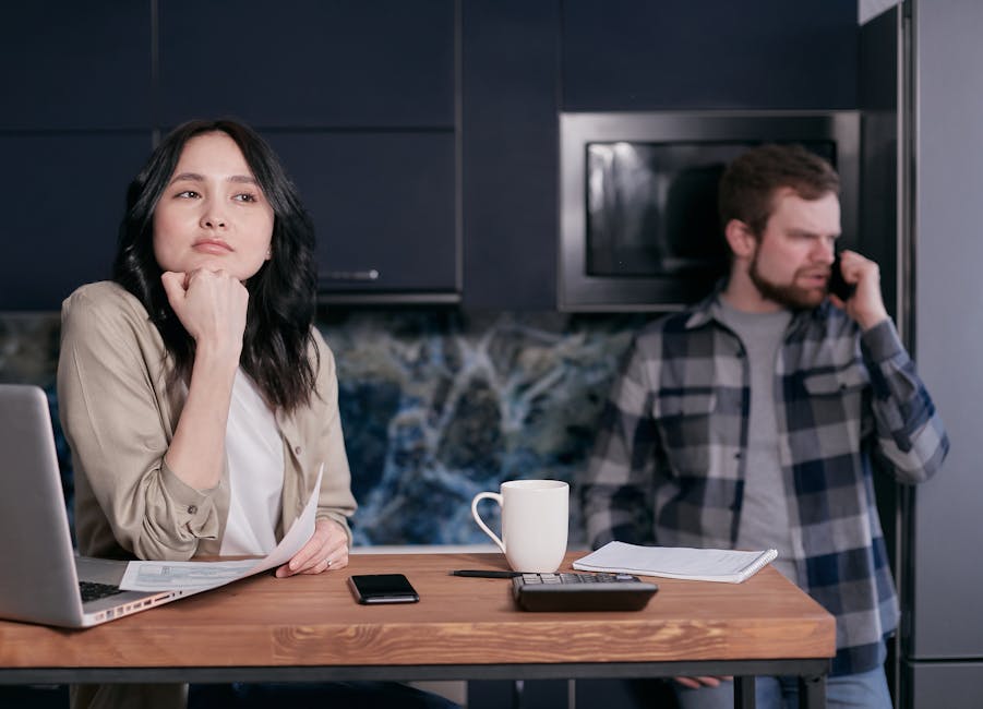 A couple in their kitchen, focused on financial planning and budgeting, showcasing stress and teamwork.